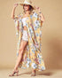 Woman wearing a floral kimono over a white outfit on a beige background
