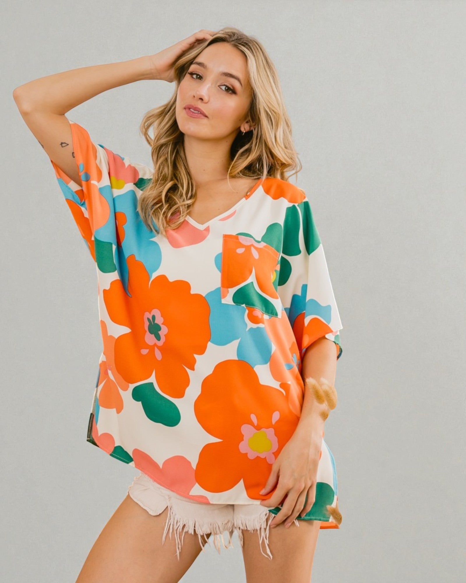 Woman wearing a colorful floral dress against a plain background