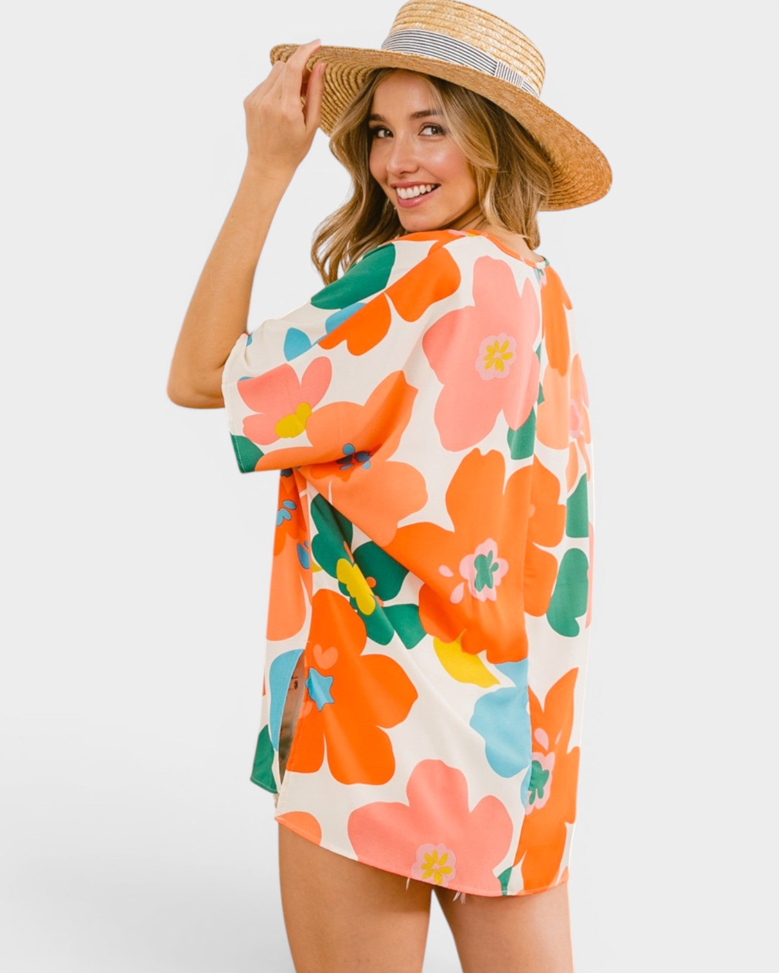 Woman wearing a colorful floral dress and straw hat on a white background