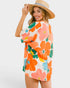 Woman wearing a colorful floral dress and straw hat on a white background