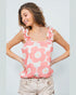 Woman wearing a pink floral tank top against a plain background