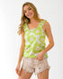 Woman wearing a green floral sleeveless top and beige shorts on a white background