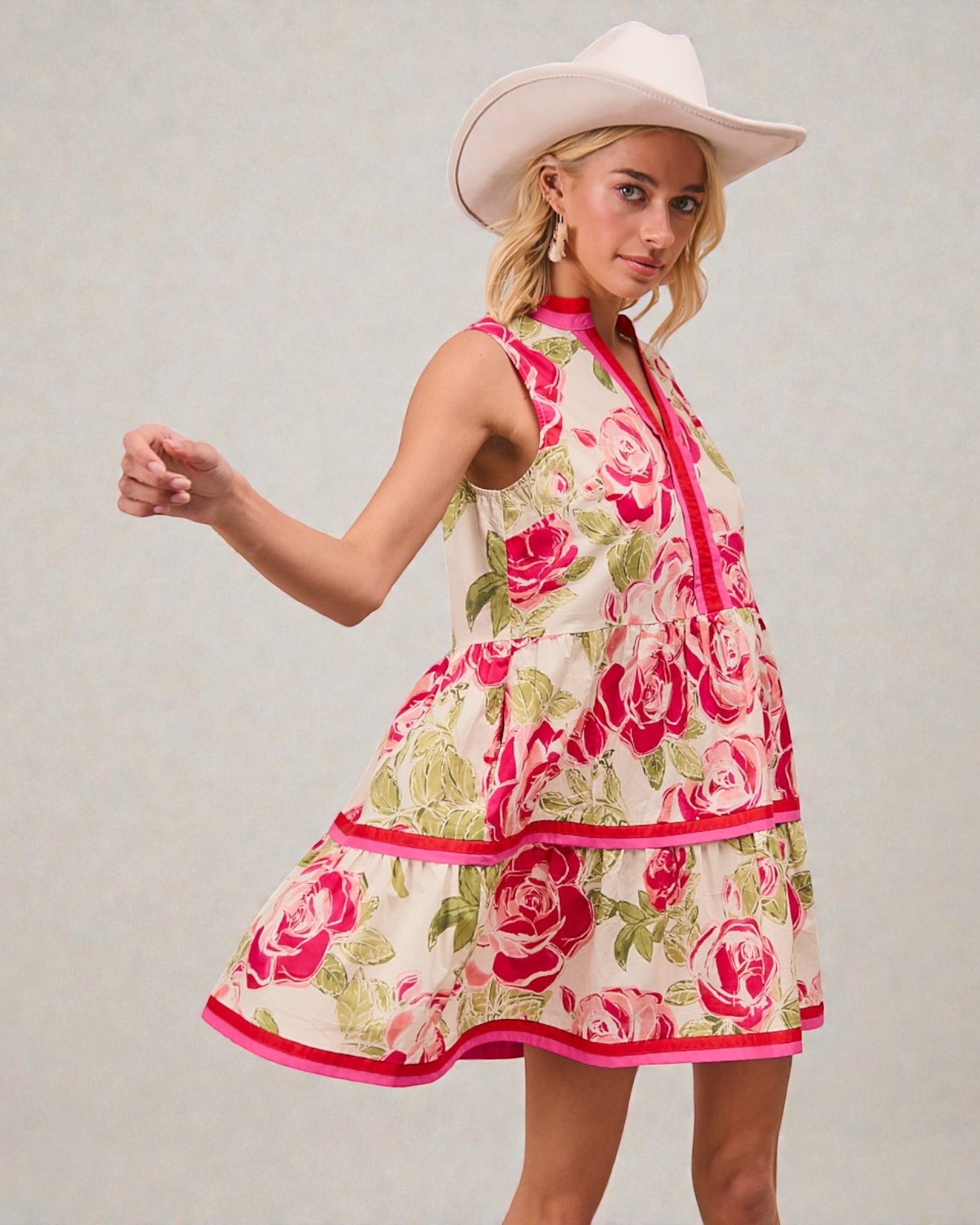 Woman wearing a floral dress and cowboy hat against a plain background