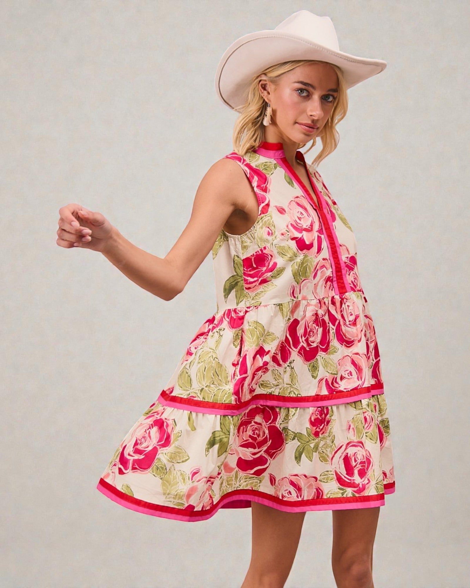 Woman wearing a floral dress and cowboy hat against a plain background