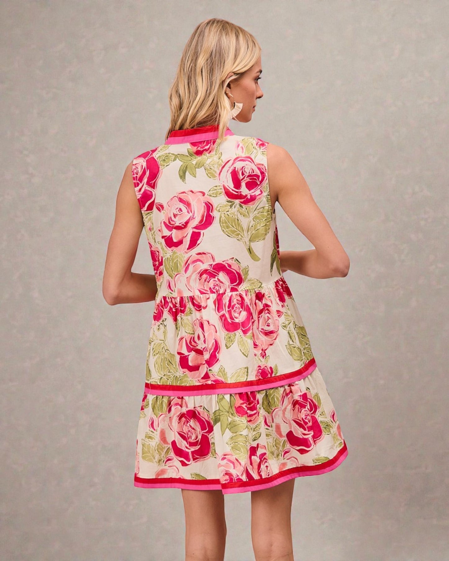 Woman wearing a floral dress with pink roses on a plain background