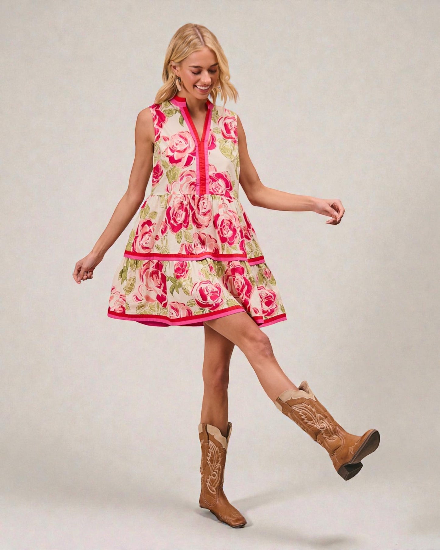 Woman wearing a floral dress and cowboy boots on a plain background