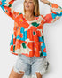 Woman wearing a colorful floral blouse with long sleeves and denim shorts on a white background