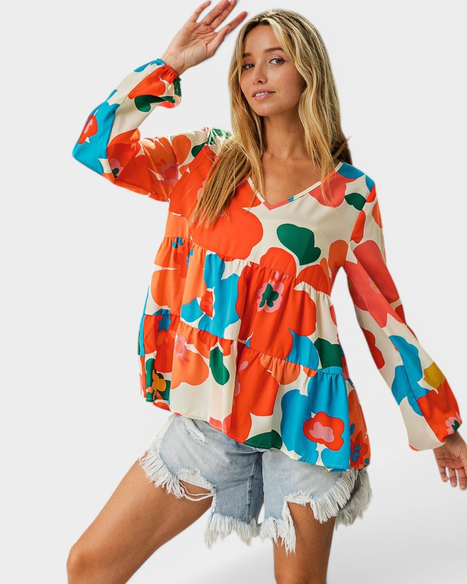 Woman wearing a colorful floral blouse with denim shorts on a white background