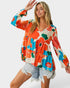 Woman wearing a colorful floral blouse with denim shorts on a white background