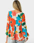 Woman wearing a colorful floral blouse on a white background