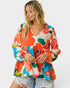 Woman wearing a colorful floral blouse against a white background