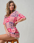 Woman wearing a pink and purple floral patterned sweater on a gray background