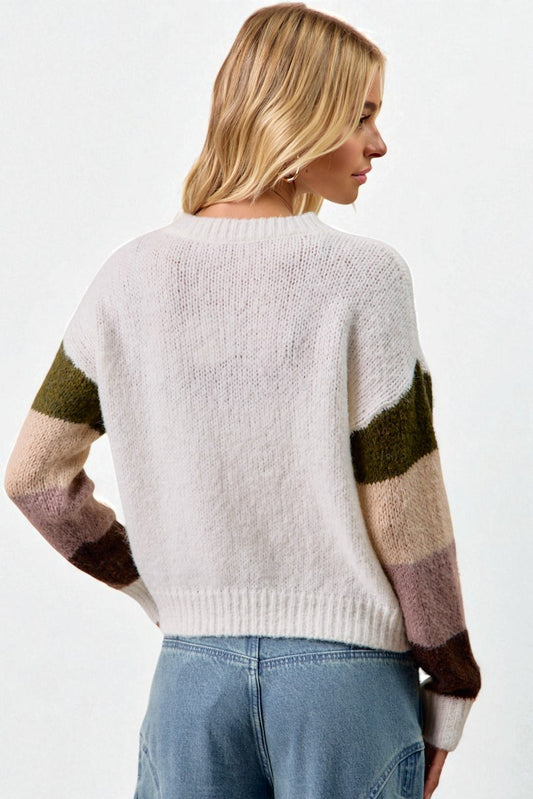 Woman wearing a white sweater with green and brown sleeves on a white background