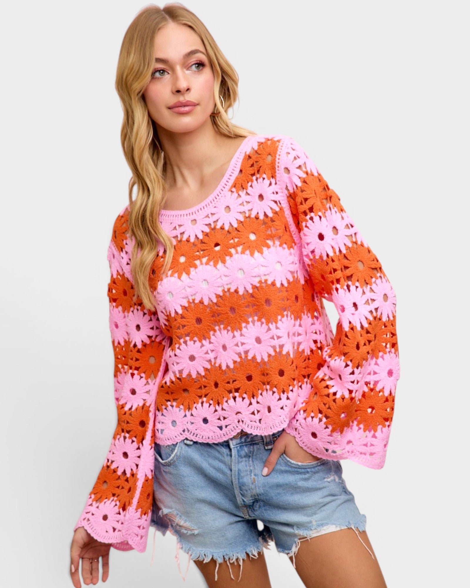 Woman wearing a colorful crochet sweater with pink flowers on a light gray background