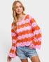 Woman wearing a colorful crochet sweater with pink flowers on a light gray background