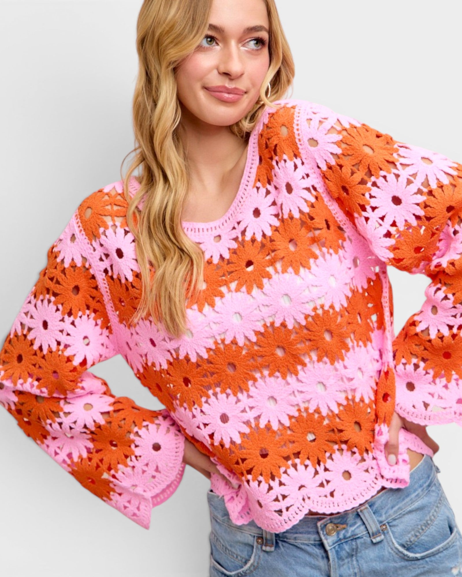 Woman wearing a colorful crochet top with bell sleeves on a plain background
