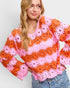 Woman wearing a colorful crochet top with bell sleeves on a plain background