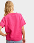 Person wearing a bright pink knitted sweater on a plain background