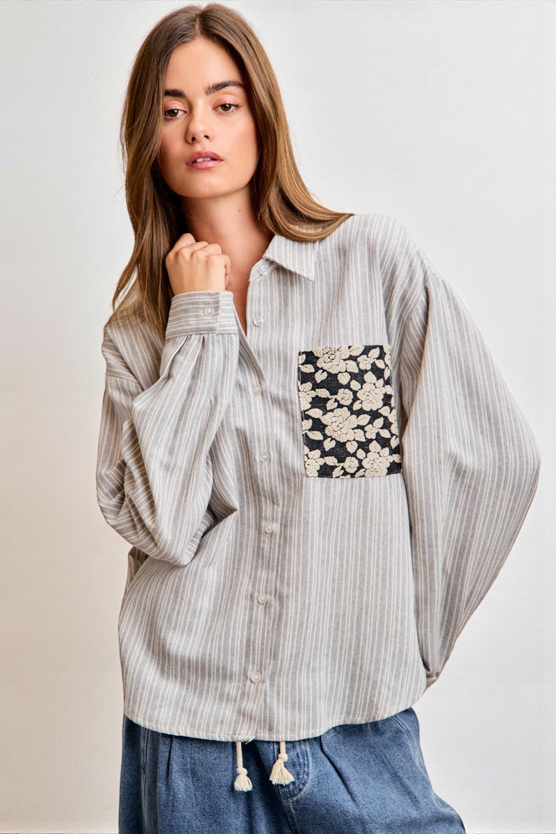 Woman wearing a striped shirt with a floral pocket on a plain background