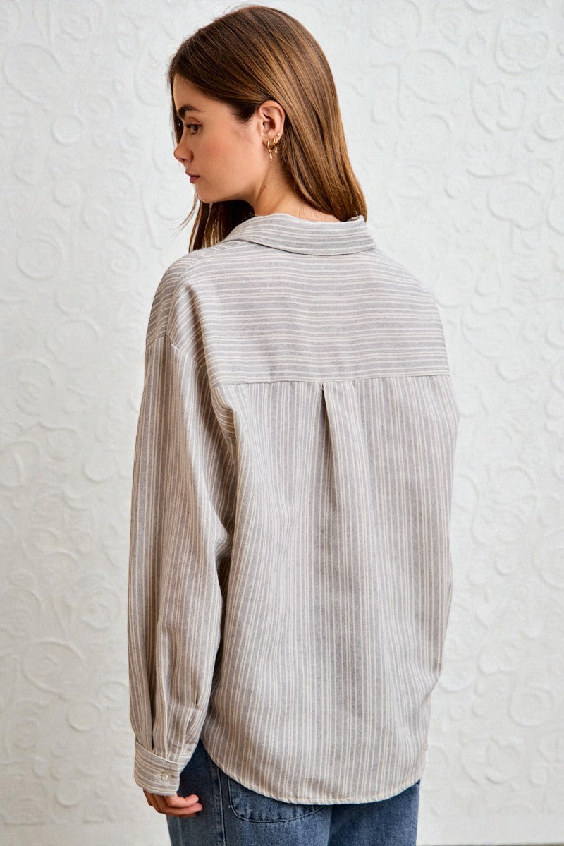 Woman wearing a light gray striped shirt against a white textured wall