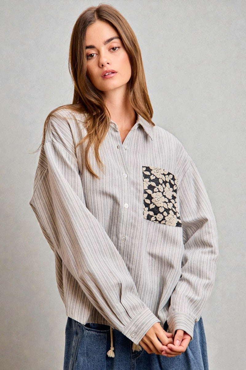 Woman wearing a striped shirt with a floral pocket design on a gray background