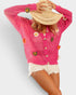 Person wearing a pink crochet cardigan with floral and button details on a plain background
