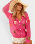 Woman wearing a pink crochet cardigan with floral embellishments on a white background