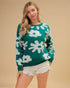 Woman wearing a green sweater with white floral patterns on a beige background