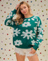 Woman wearing a green sweater with white floral patterns against a polka dot background