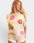 Woman wearing a sleeveless sweater with floral patterns on a plain background