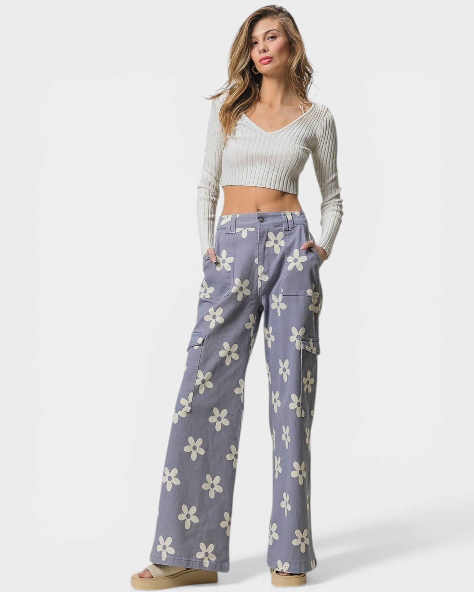 Woman wearing a white crop top and blue floral pants on a white background