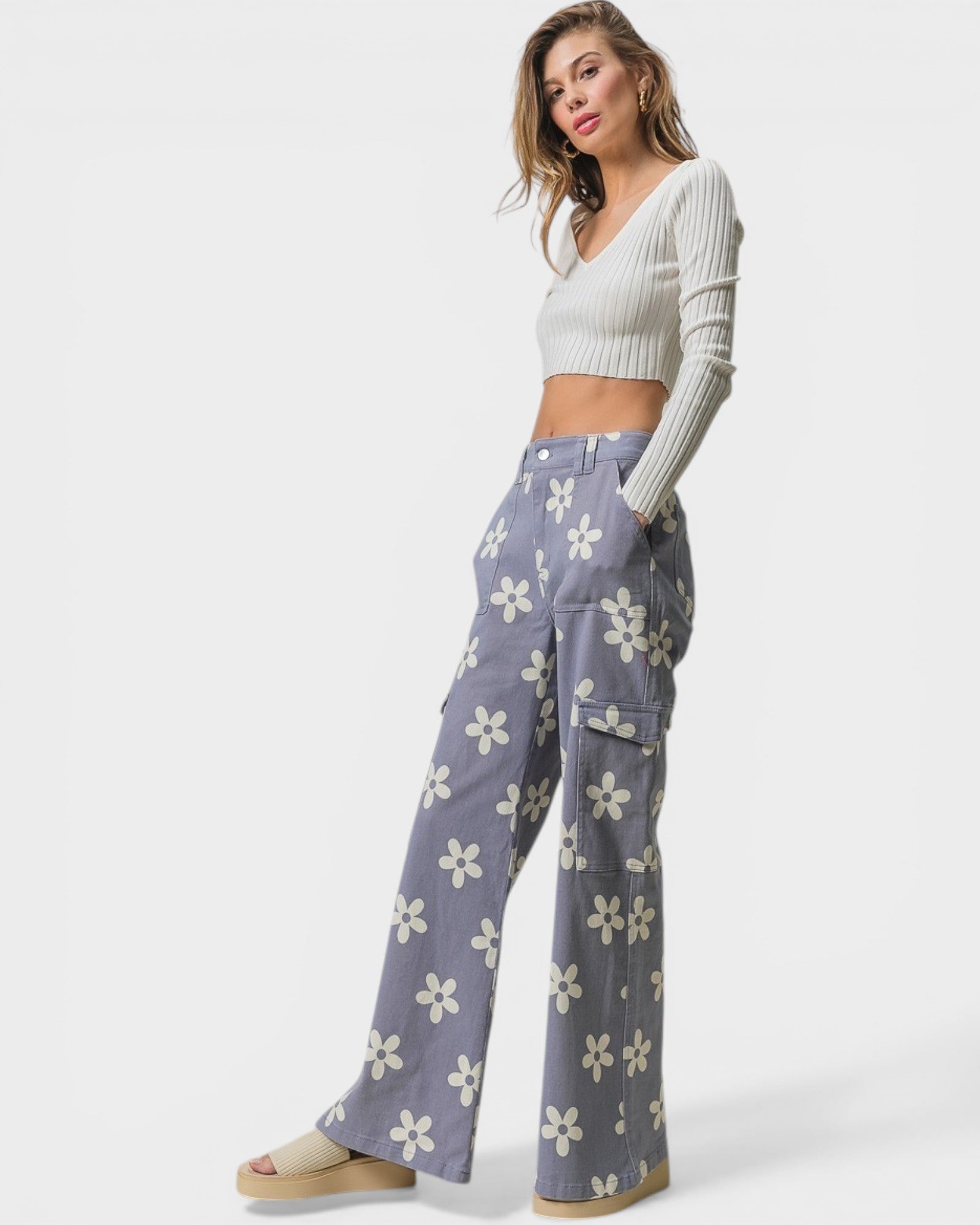 Woman wearing a white cropped sweater and floral pants on a white background