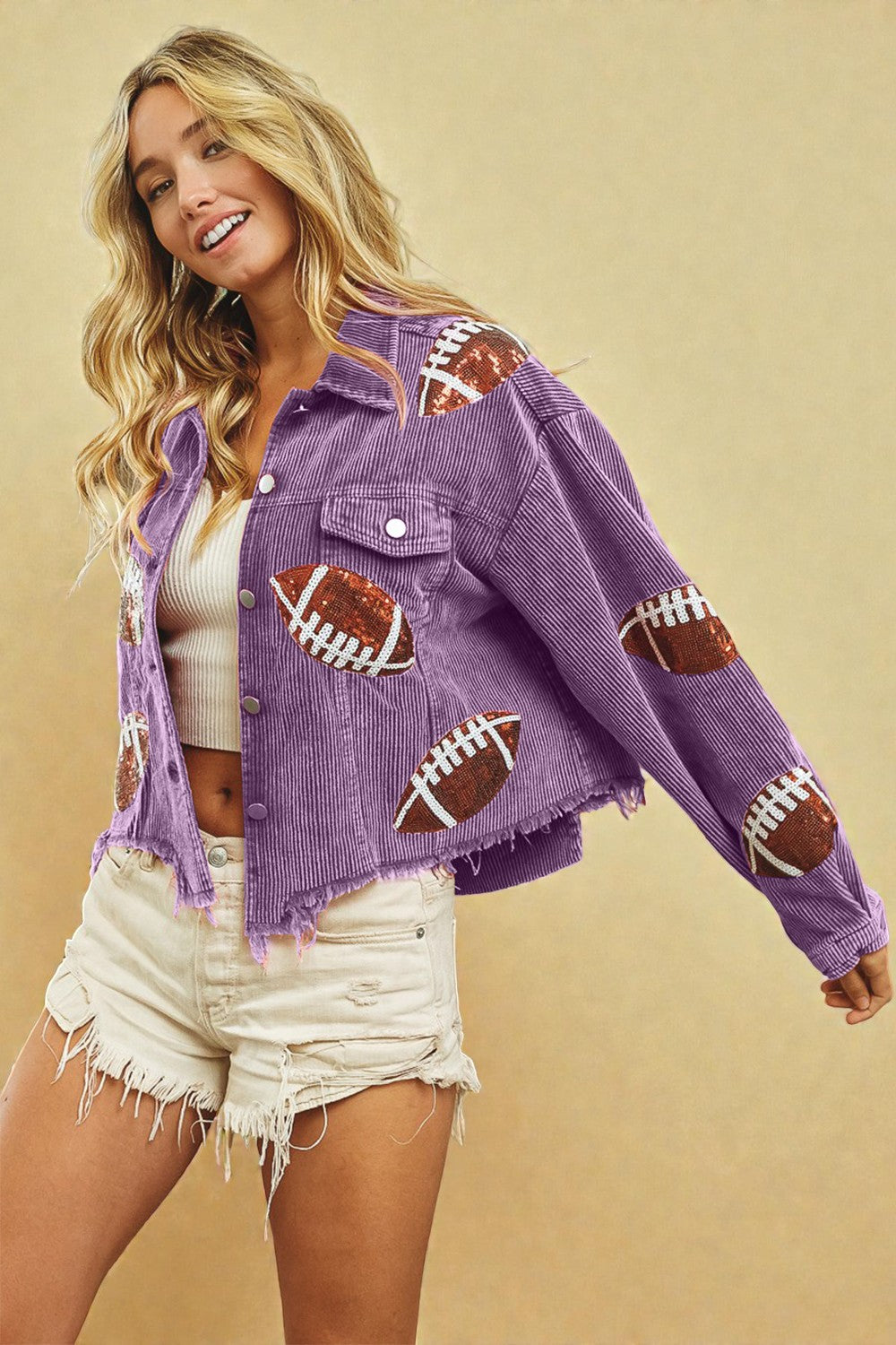 Woman wearing a purple jacket with football patches on a beige background