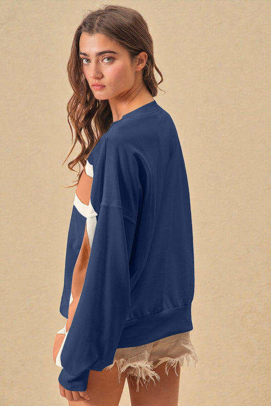 Woman wearing a navy blue sweatshirt over a white top with beige shorts on a beige background