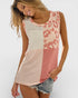 Woman wearing a sleeveless top with pink and white pattern on a plain background