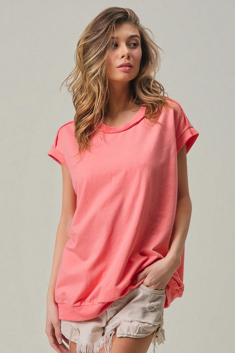 Woman wearing a coral pink t-shirt against a plain background