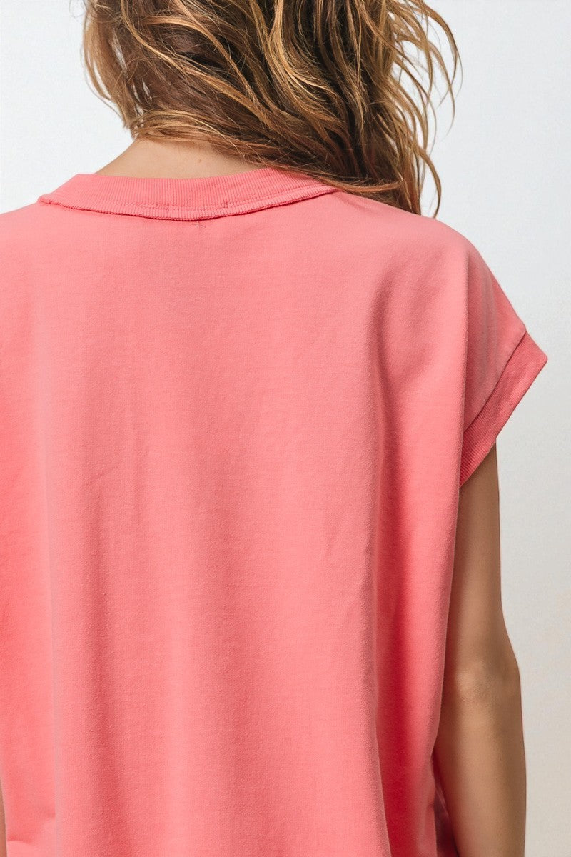 Coral-colored sleeveless top worn by a person on a white background