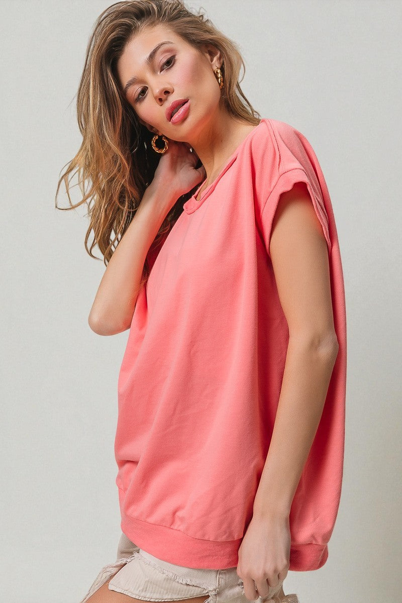 Woman wearing a pink sleeveless top against a plain background