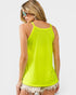 Woman wearing a bright green tank top and white shorts on a light gray background