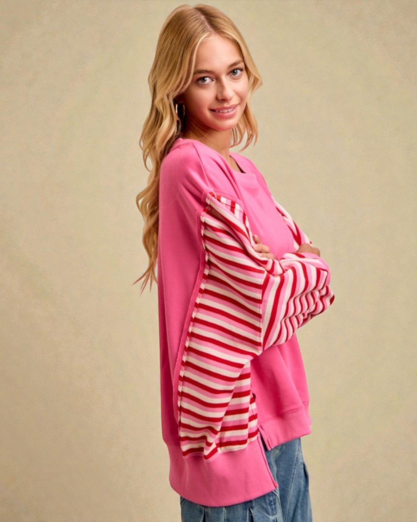Woman wearing a pink cardigan with a striped pattern over it on a beige background