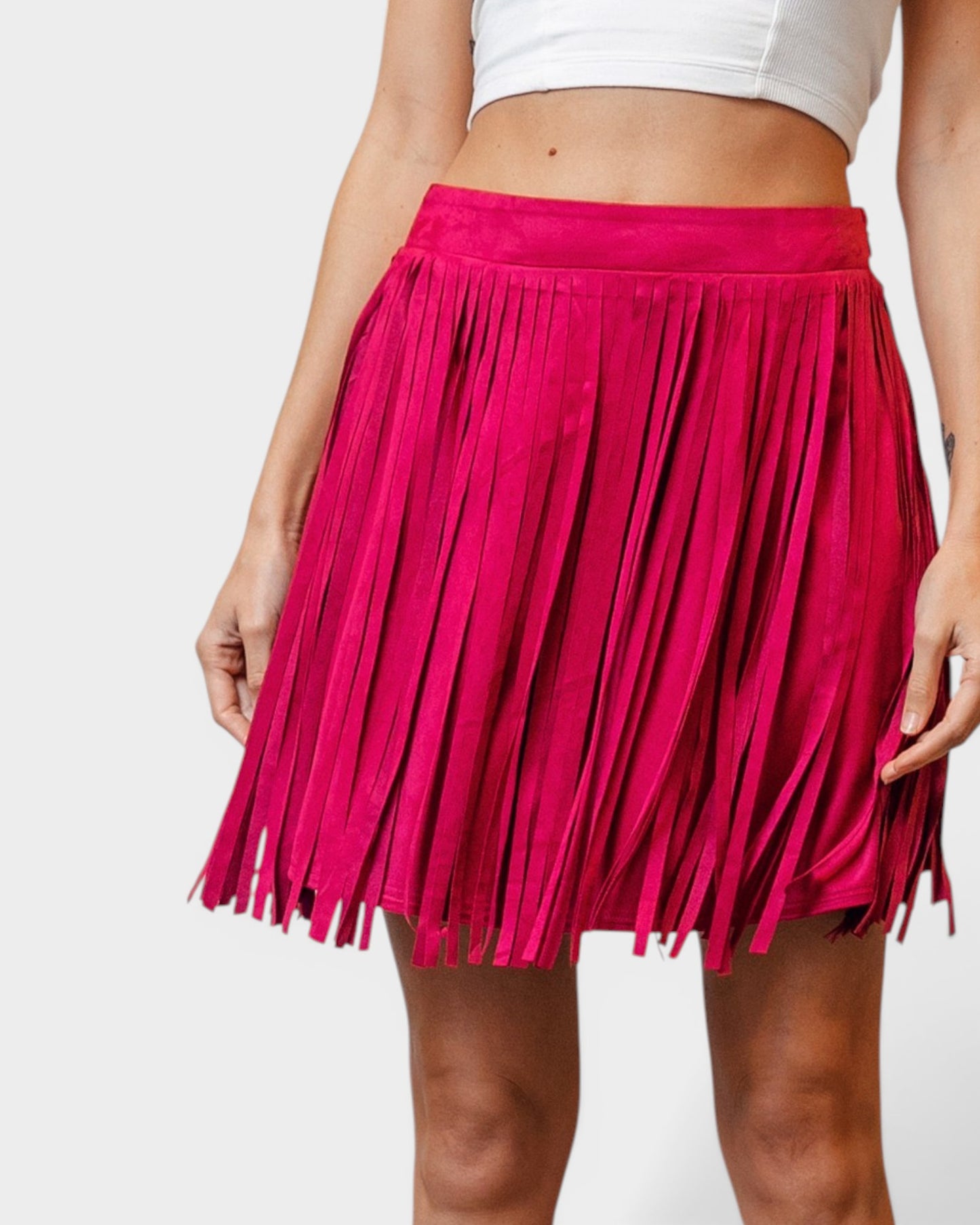 Person wearing a bright pink fringed skirt on a white background