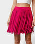 Person wearing a bright pink fringed skirt on a white background