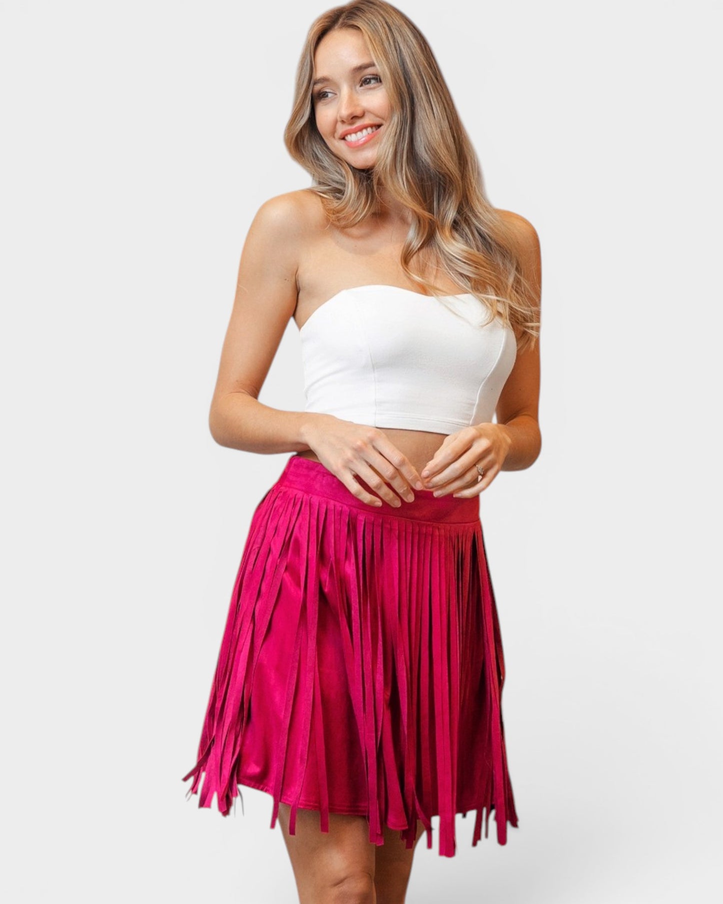 Woman wearing a white strapless top and pink fringed skirt on a white background