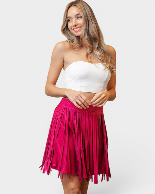 Woman wearing a white strapless top and pink fringed skirt on a white background