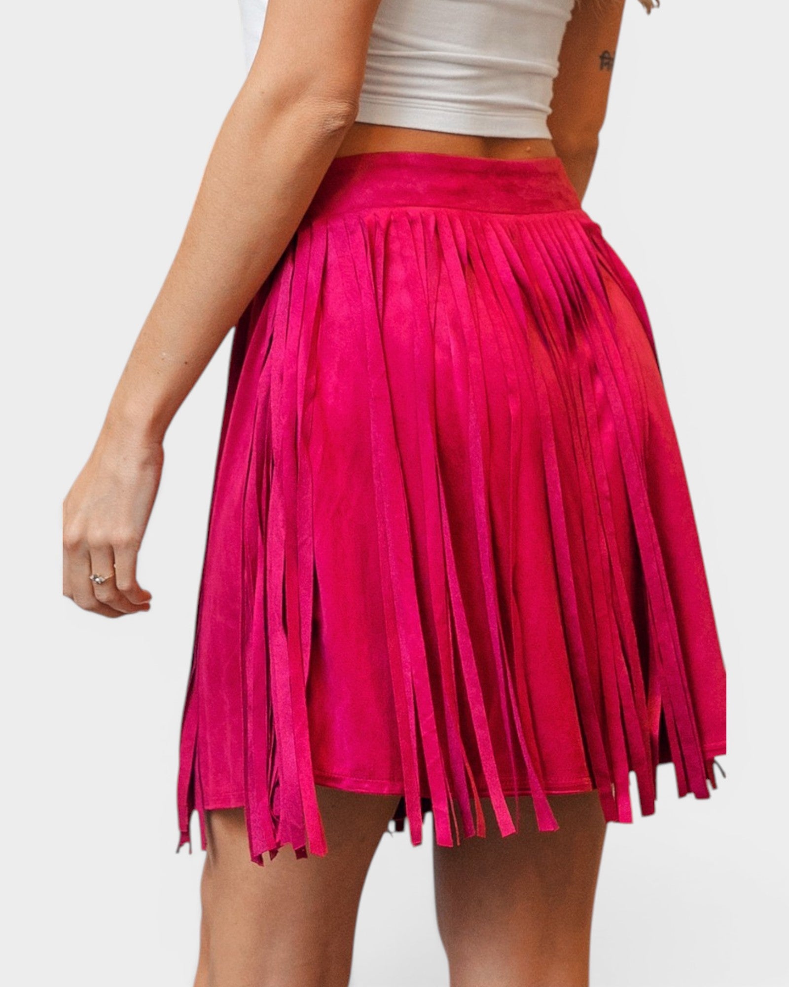 Pink fringed skirt worn by a person on a white background
