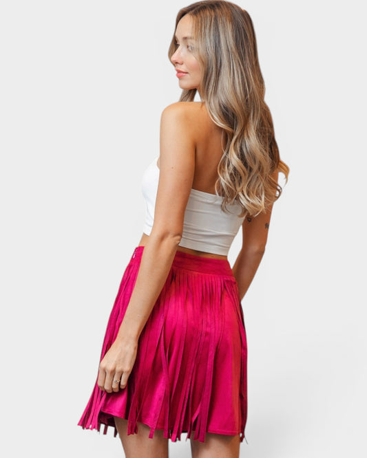 Woman wearing a white top and bright pink skirt on a white background