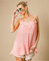 Woman wearing a pink dress with lace details on a beige background