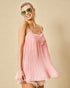 Woman wearing a pink dress with lace details against a beige background