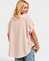 Woman wearing a beige oversized top and blue jeans on a white background