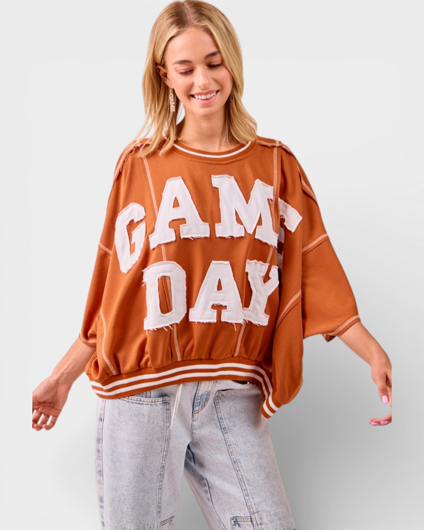 Woman wearing a 'GAMEDAY' oversized sweater on a plain background